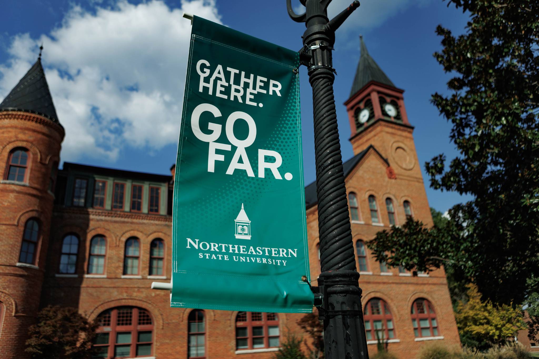 NSU Gather Here. Go Far. Northeastern State University banner displayed in front of historic Seminary Hall on the Tahlequah campus.