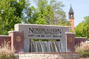 NSU Tahlequah Entrance Fountain with green trees and the Seminary Hall Clock Tower in the background