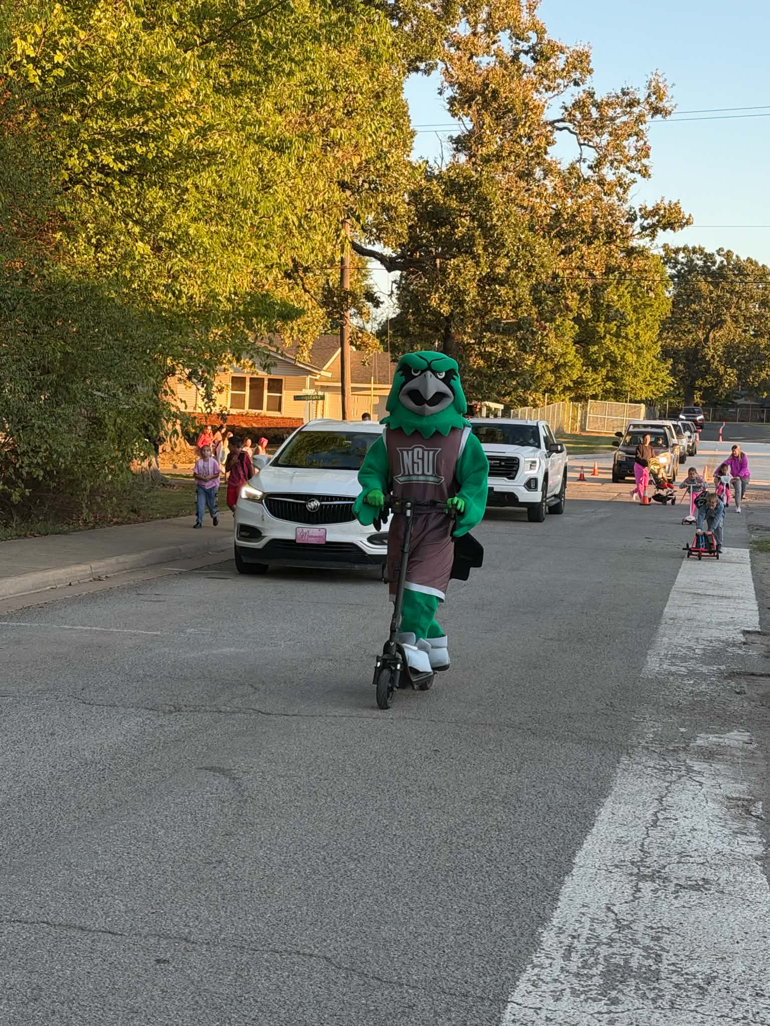 Rowdy the RiverHawk rides a scooter alongside Cherokee Elementary students during the Walk and Roll event on Oct. 7. 
